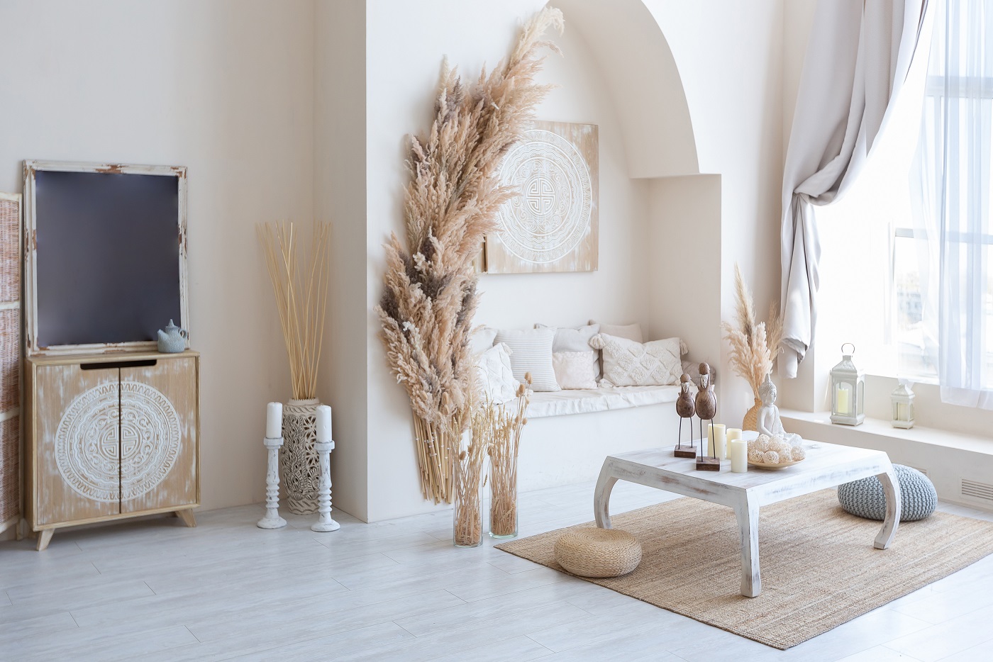 daylight through a huge panoramic window illuminates the cozy oriental interior of the room in beige colors with wicker furniture and authentic elements