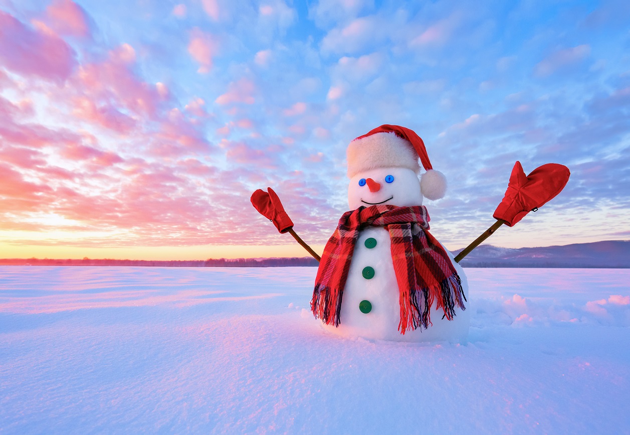 a snow man wearing gloves, scarf and a santa hat over the sunset