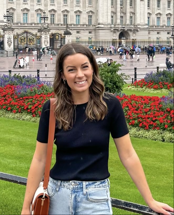 a picture of a woman with flowers and building in the background